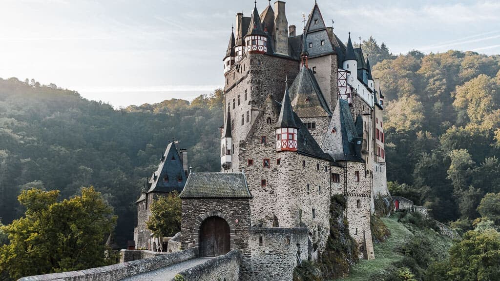 Burg Eltz im Moseltal umgeben von bewaldeten Hügeln und Weinbergen